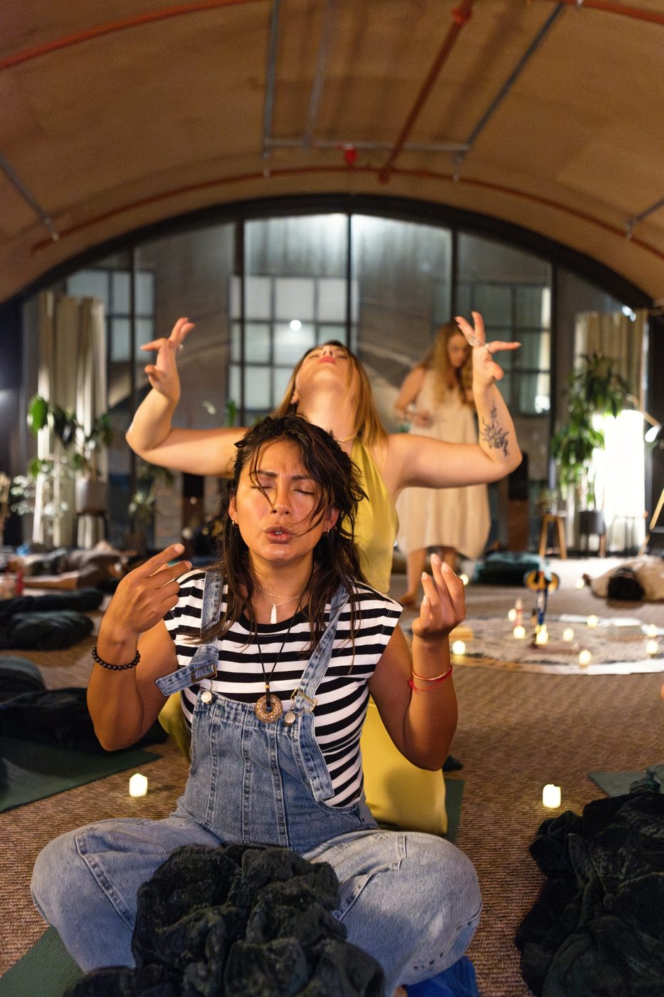 A participant with open hands and a softened expression, both facilitators behind